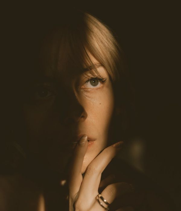 Woman performing a calm yoga pose in a dark room with golden light.